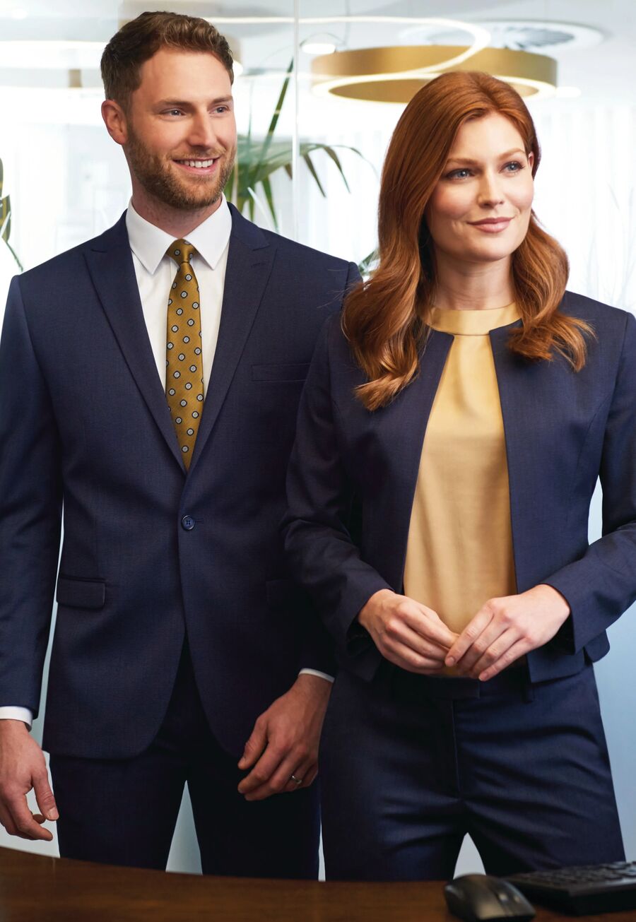 Two members of front-of-house staff in tailored navy suits at a reception desk